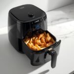 Cosori 6QT TurboBlaze Air Fryer on a kitchen counter with crispy french fries and chicken wings