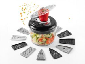 The Fullstar 4-in-1 Vegetable Chopper in white surrounded by freshly chopped vegetables like cucumbers, carrots, and onions on a kitchen counter.