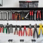 Organized garage wall with TIDYME tool organizer rack holding various tools on a pegboard